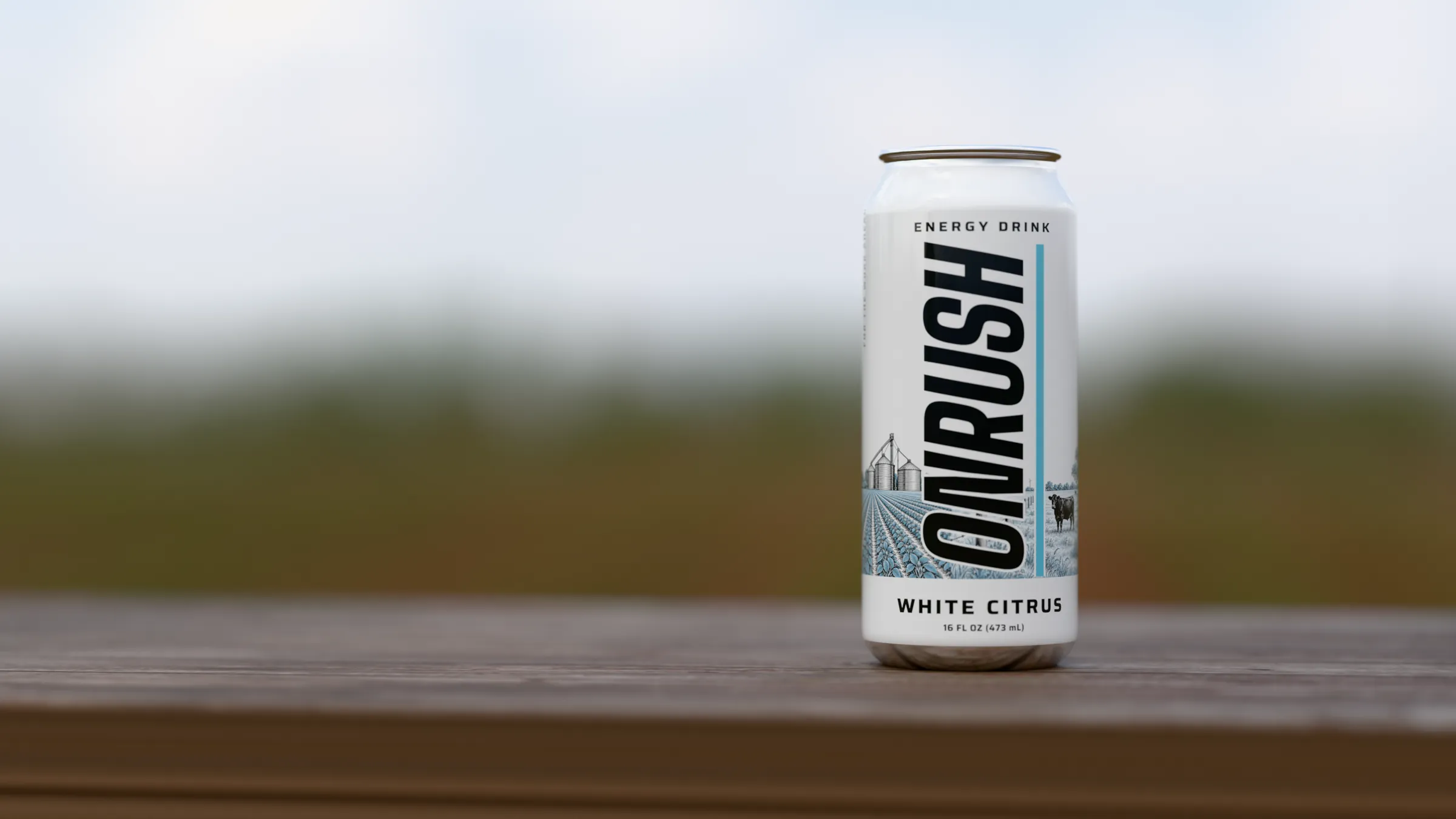 A cold ONRUSH can on a weathered plank at the edge of a planted field, rows running to the horizon.